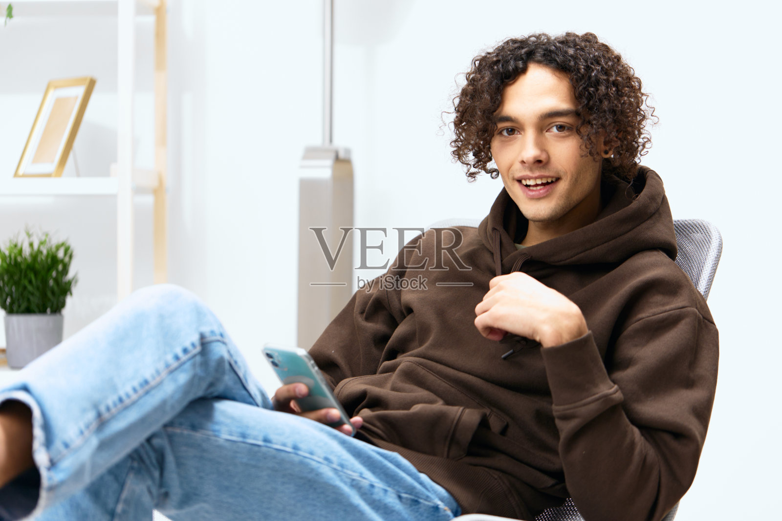 一个年轻人坐在椅子上用电话交流室内灯光背景照片摄影图片