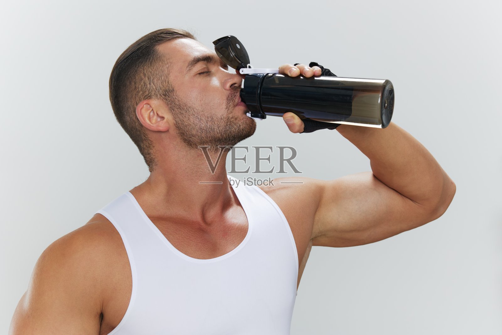 男士运动休息时喝水,男士健身教练在家健身,养生美体的理念照片摄影图片