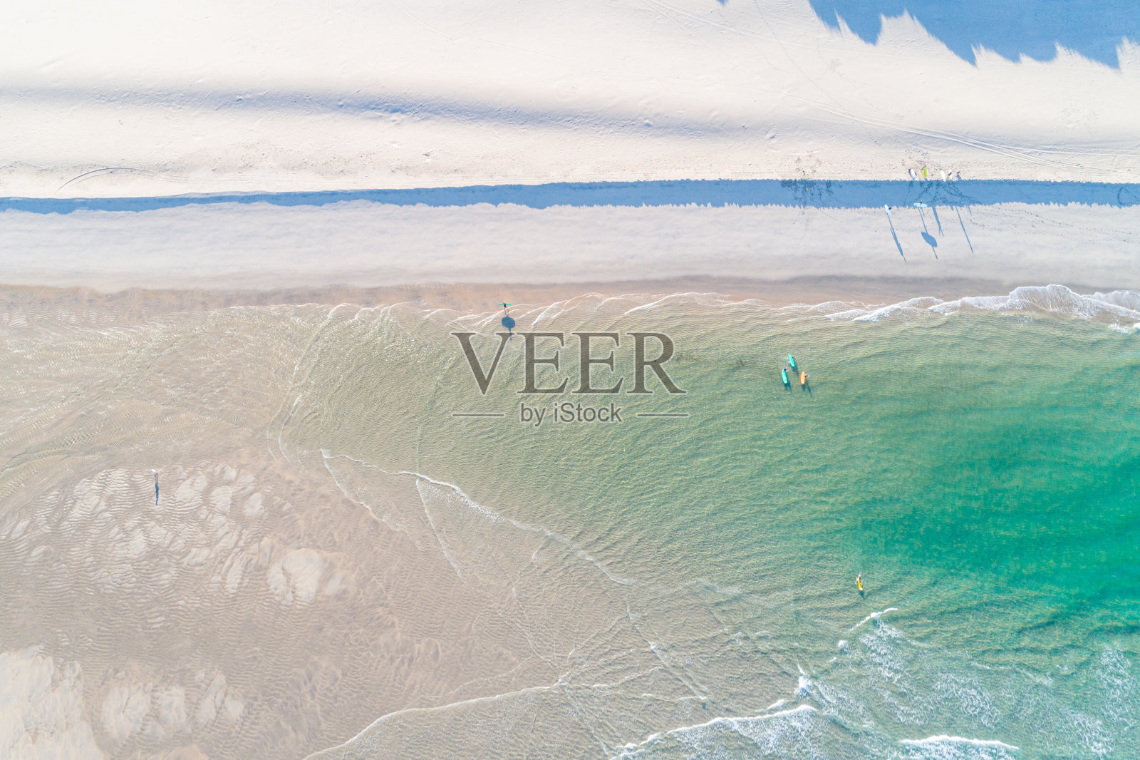 在海滩上用冲浪板冲浪的人。夏天碧绿的海水和干净的海滩。无人机俯视图。海景鸟瞰图。夏季的娱乐和运动照片摄影图片