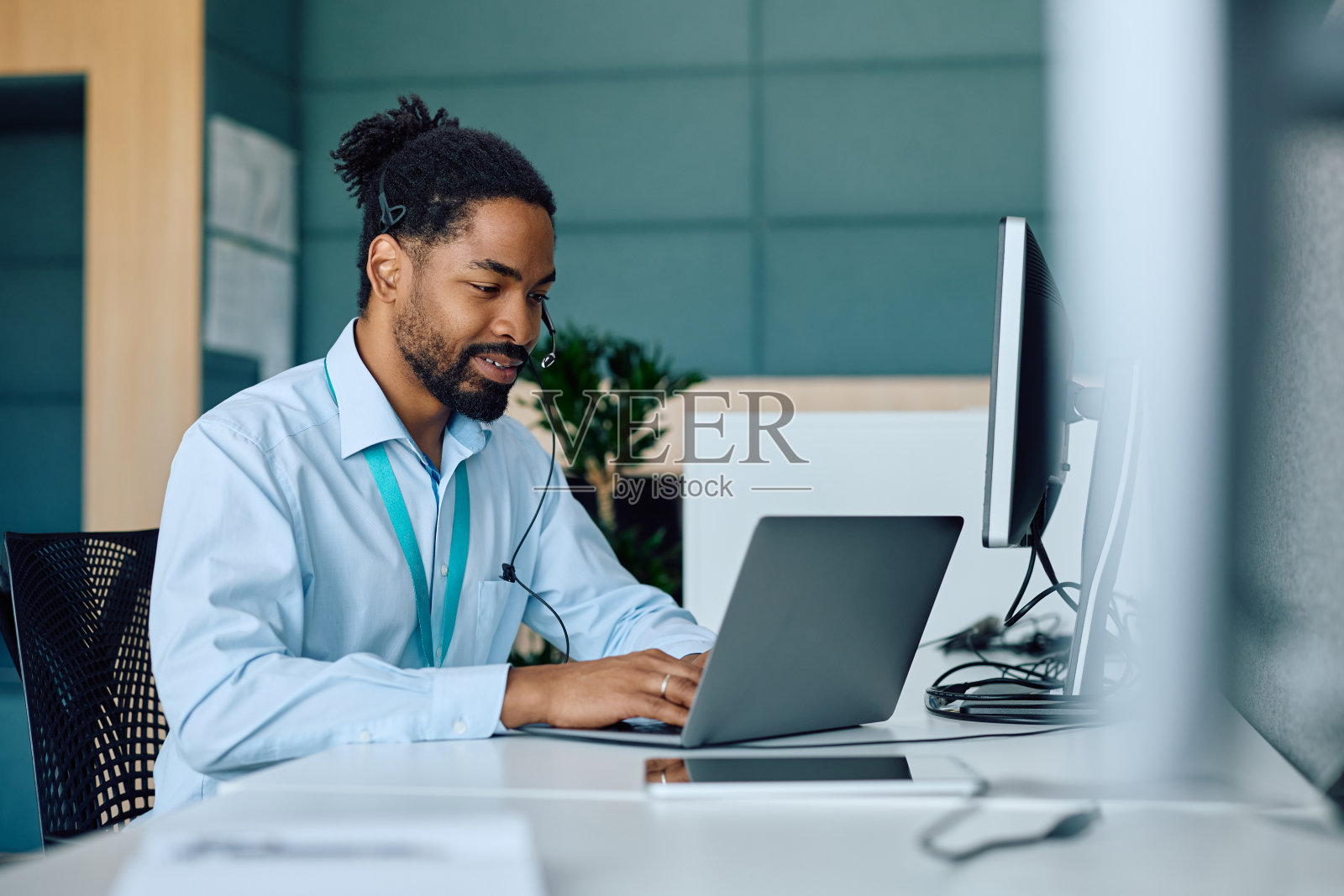 微笑的黑人商人在办公室用笔记本电脑工作。照片摄影图片