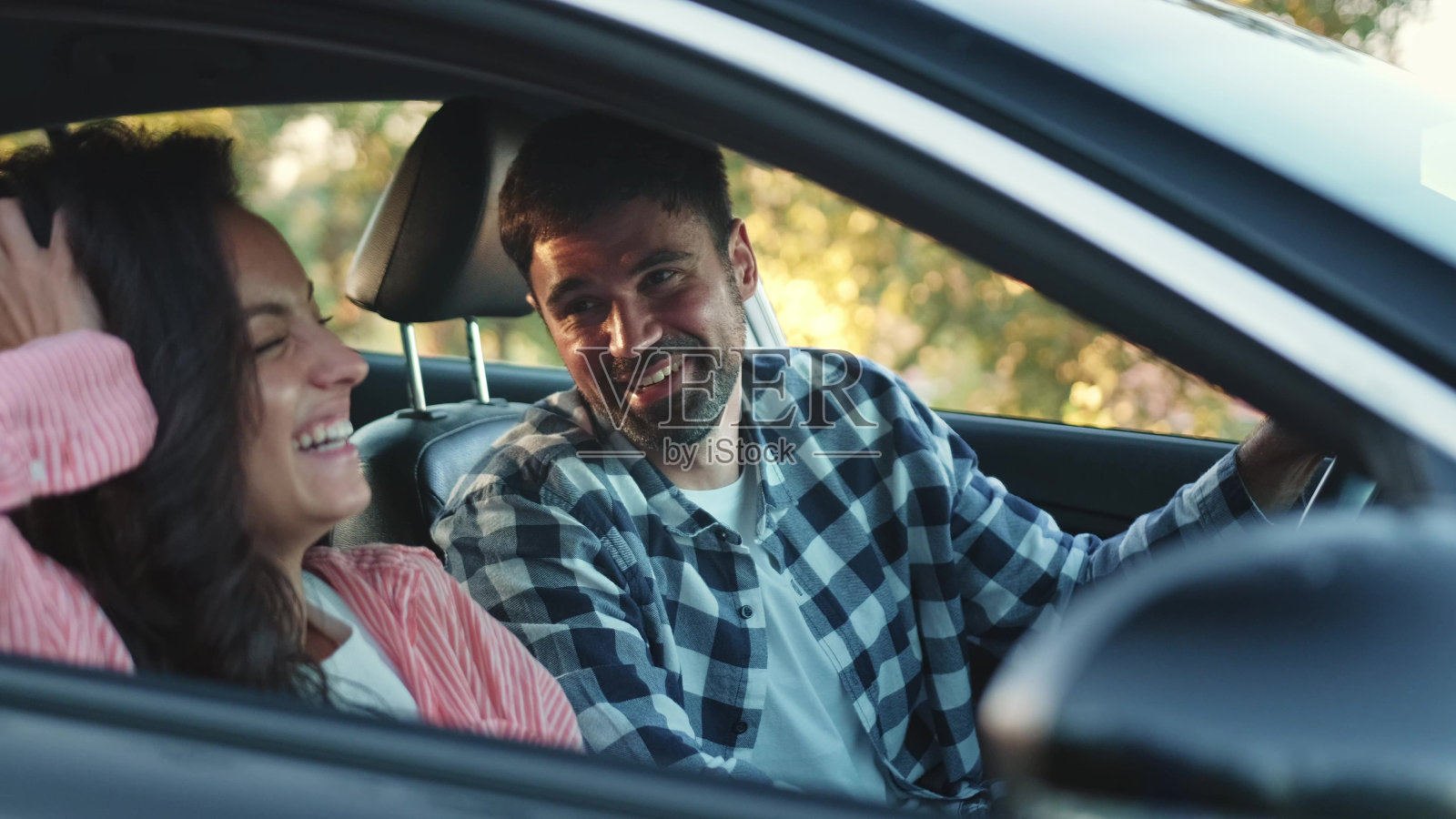 一个快乐的女人坐在她男朋友旁边的车里。慢动作照片摄影图片