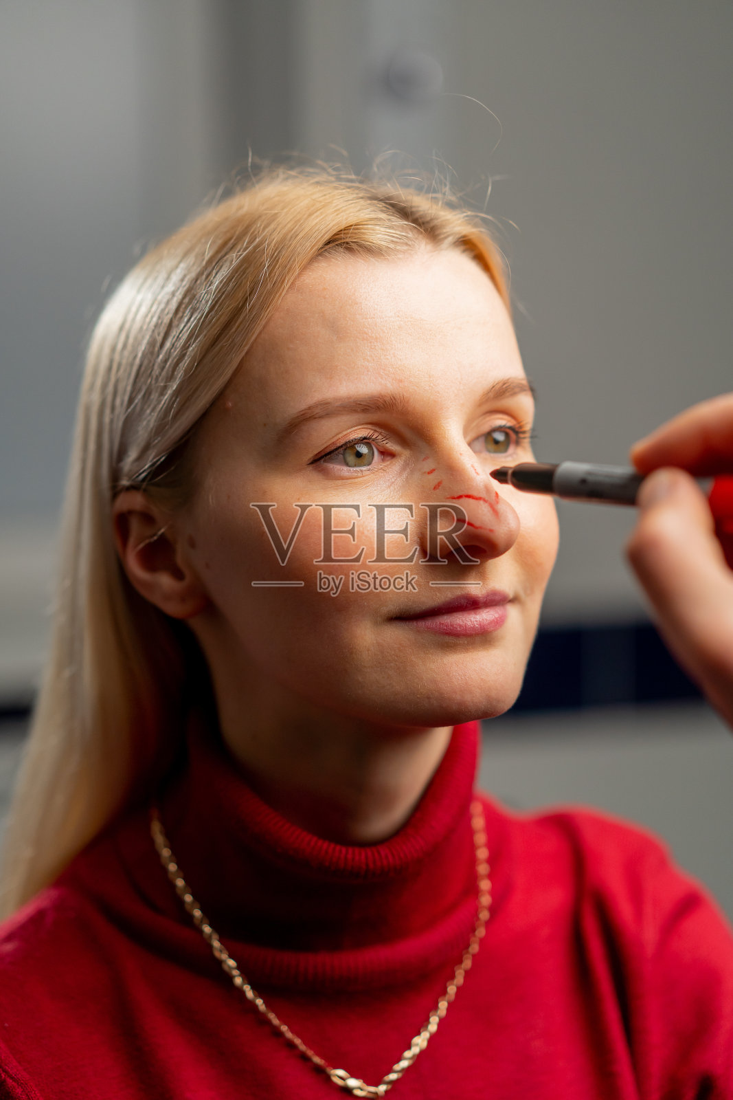 在整形外科诊所,医生在手术前在一个小女孩的脸上做标记照片摄影图片