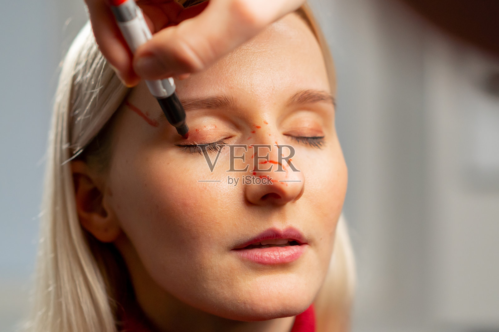 整形外科诊所里,医生在手术前在一个小女孩的脸上做标记照片摄影图片