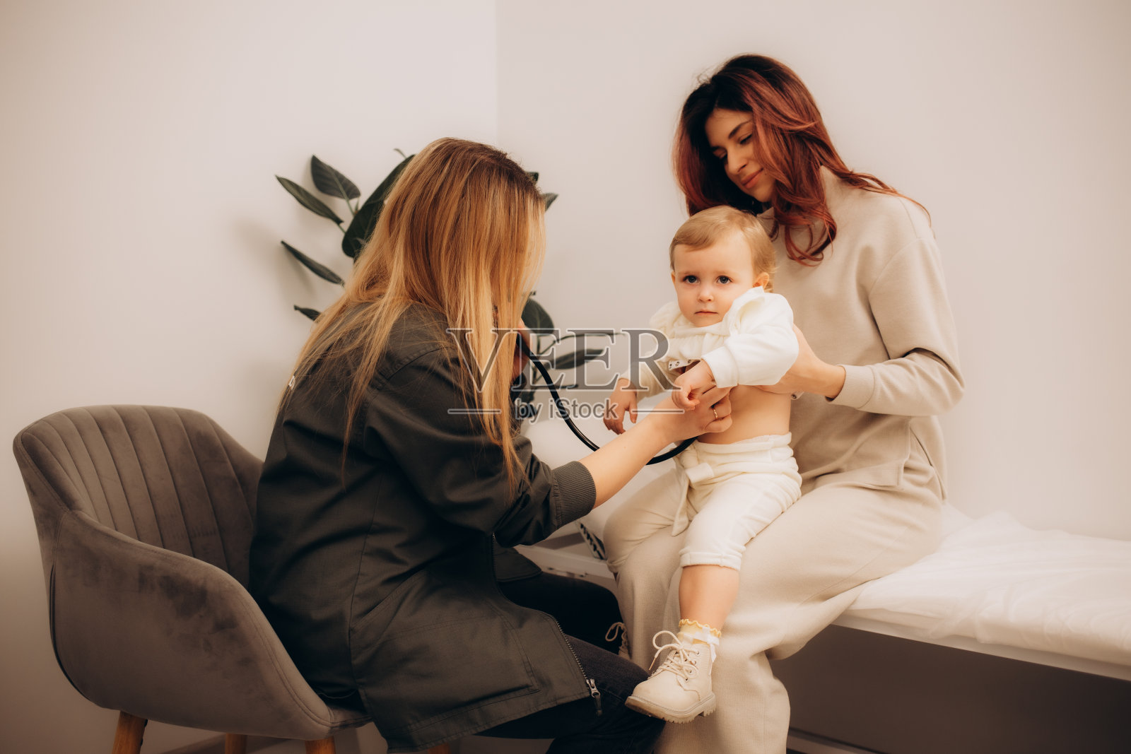 在现代诊所阳光明媚的检查室里,医生微笑着检查孩子的肺部。友好的女儿科医生用听诊器检查年轻病人的呼吸和心跳照片摄影图片