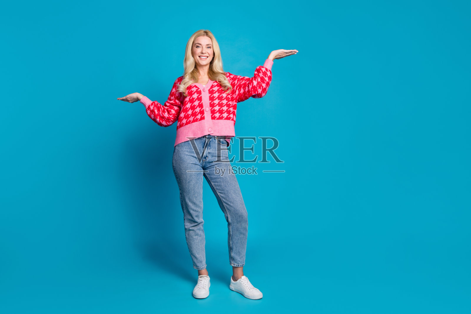 可爱的好女人穿针织印花开襟羊毛衫手掌的全长照片比较产品的空白空间孤立的蓝色背景照片摄影图片