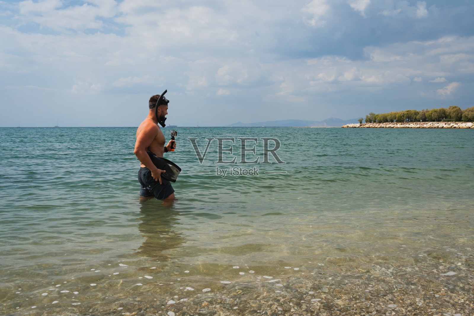 春天在希腊的海边,一个男人准备去浮潜。照片摄影图片
