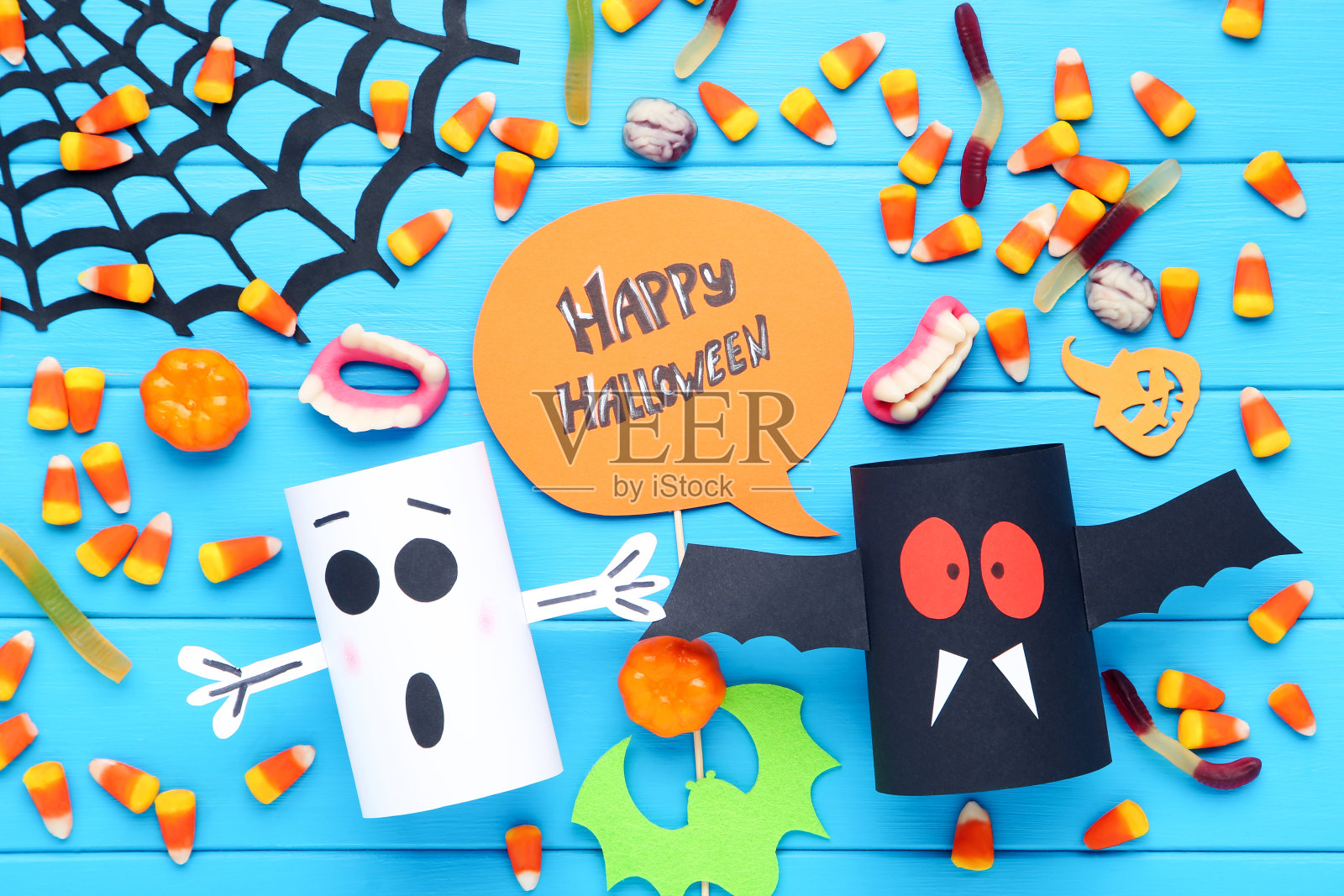 文字快乐万圣节与糖果,纸鬼,南瓜和蜘蛛网在蓝色的木制背景照片摄影图片