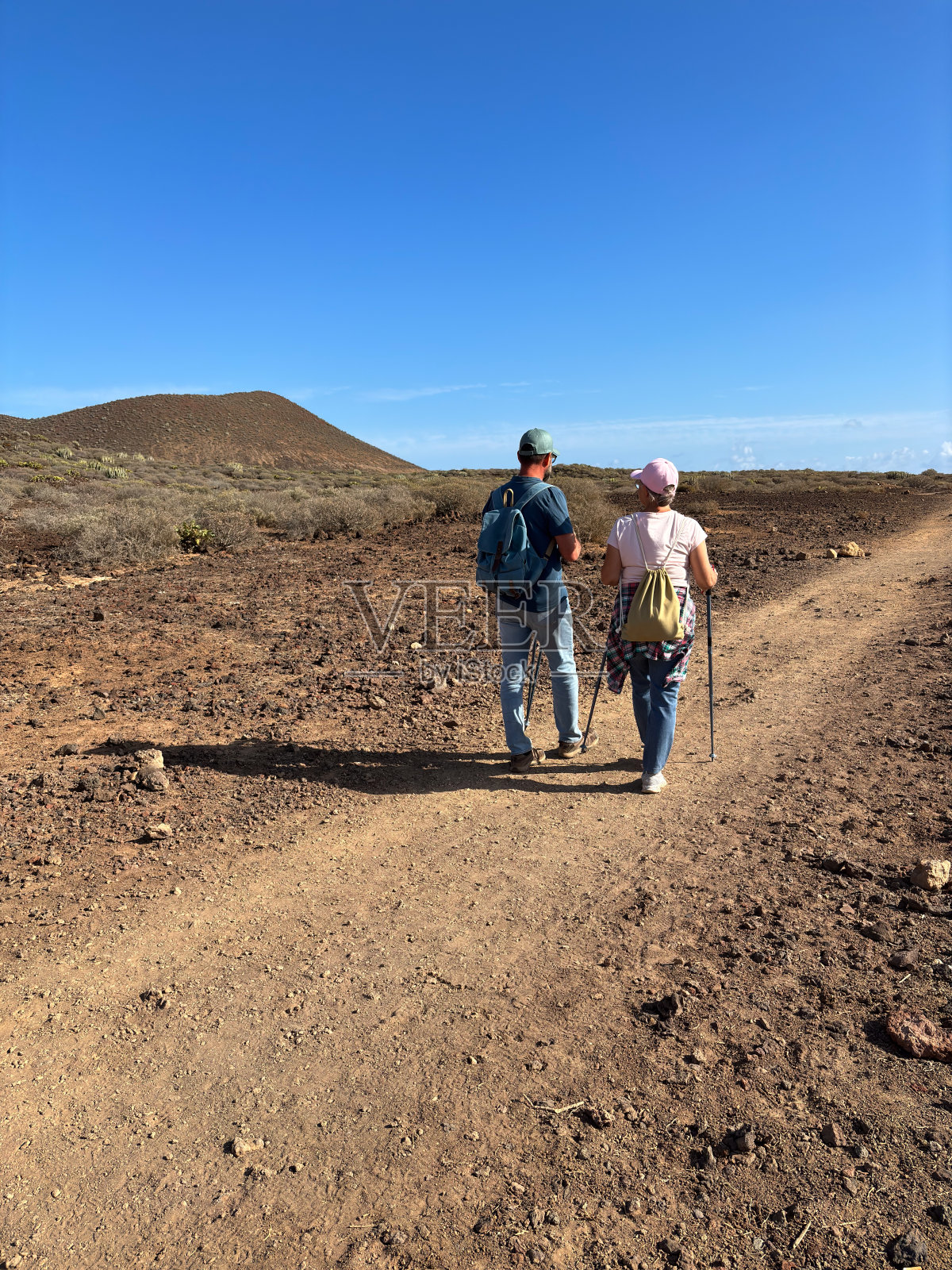 户外活动的自然概念。运动朋友的后视图,男女漫步在干旱的小径上,享受健康的生活方式和自由,美丽的风景和蓝天照片摄影图片