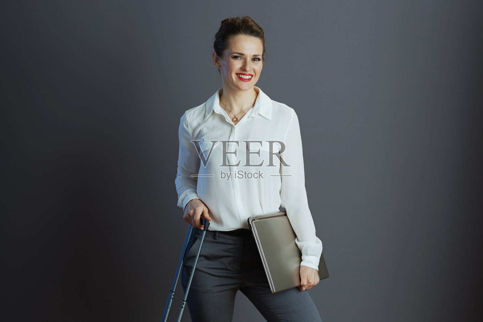 微笑的现代商务女性穿着白衬衫,孤立在灰色照片摄影图片