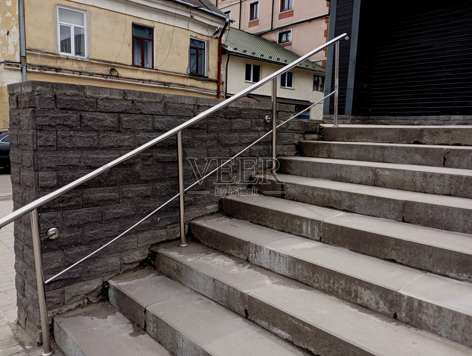 混凝土楼梯通往顶部,在城市中有一个不锈钢扶手。城市广场上的楼梯。照片摄影图片