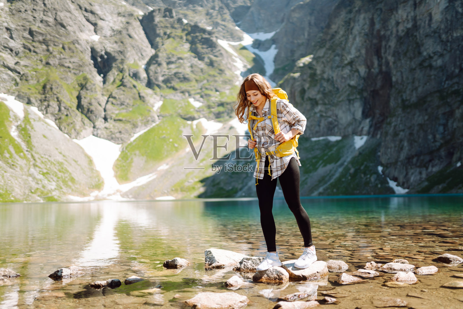 一名年轻女子背着黄色的徒步背包,在森林和悬崖之间的山间徒步旅行。照片摄影图片