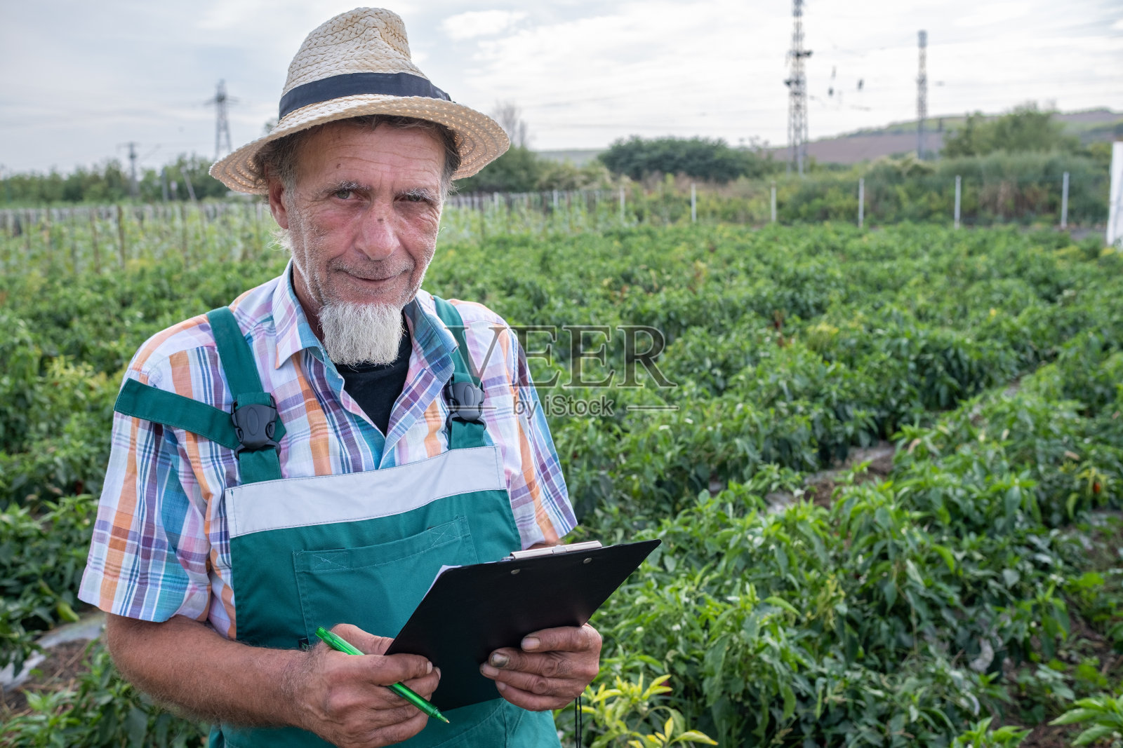 一个快乐的白胡子农民的画像,手里拿着一个剪贴板。照片摄影图片