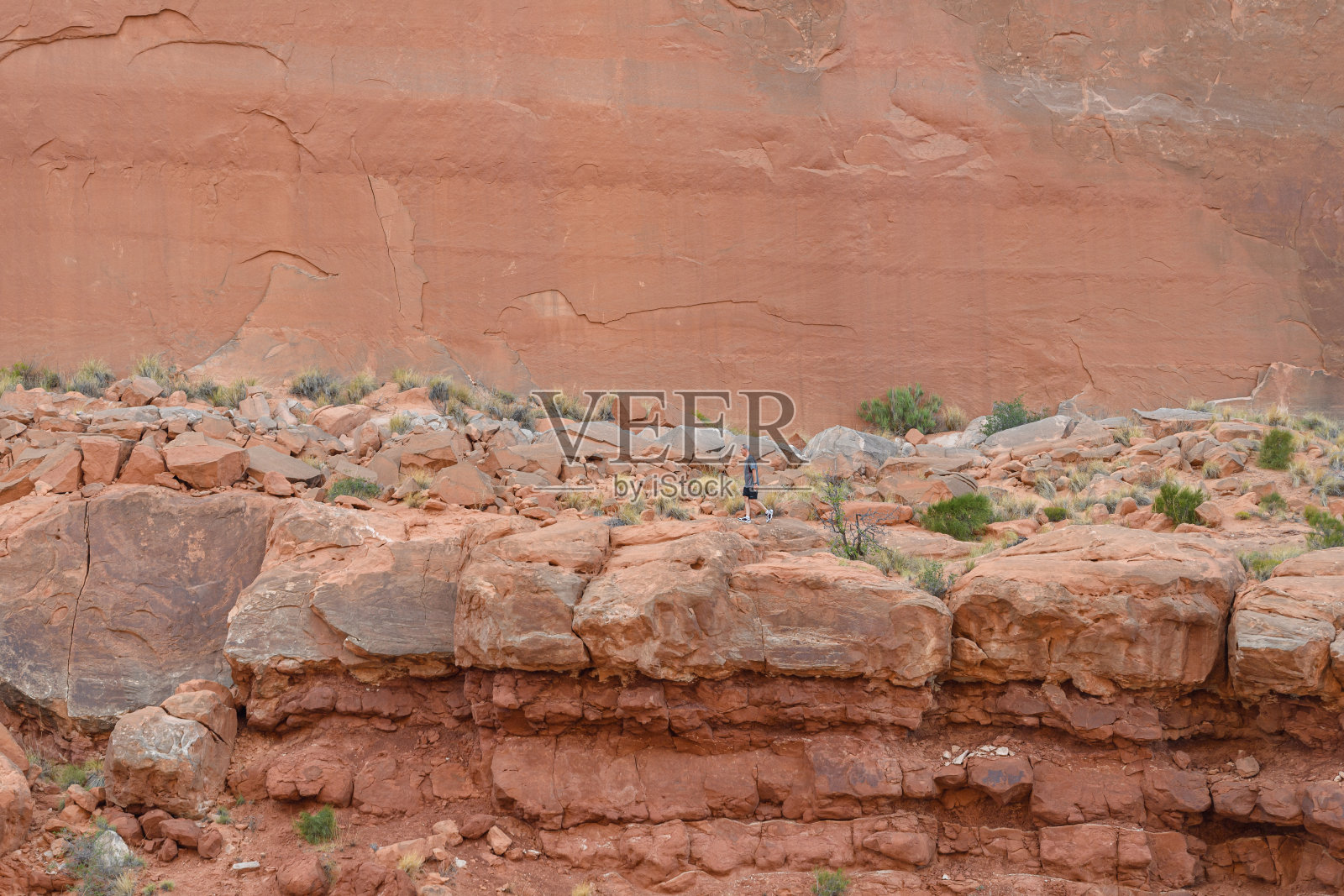 一个男人沿着公园里的红色岩石奔跑照片摄影图片