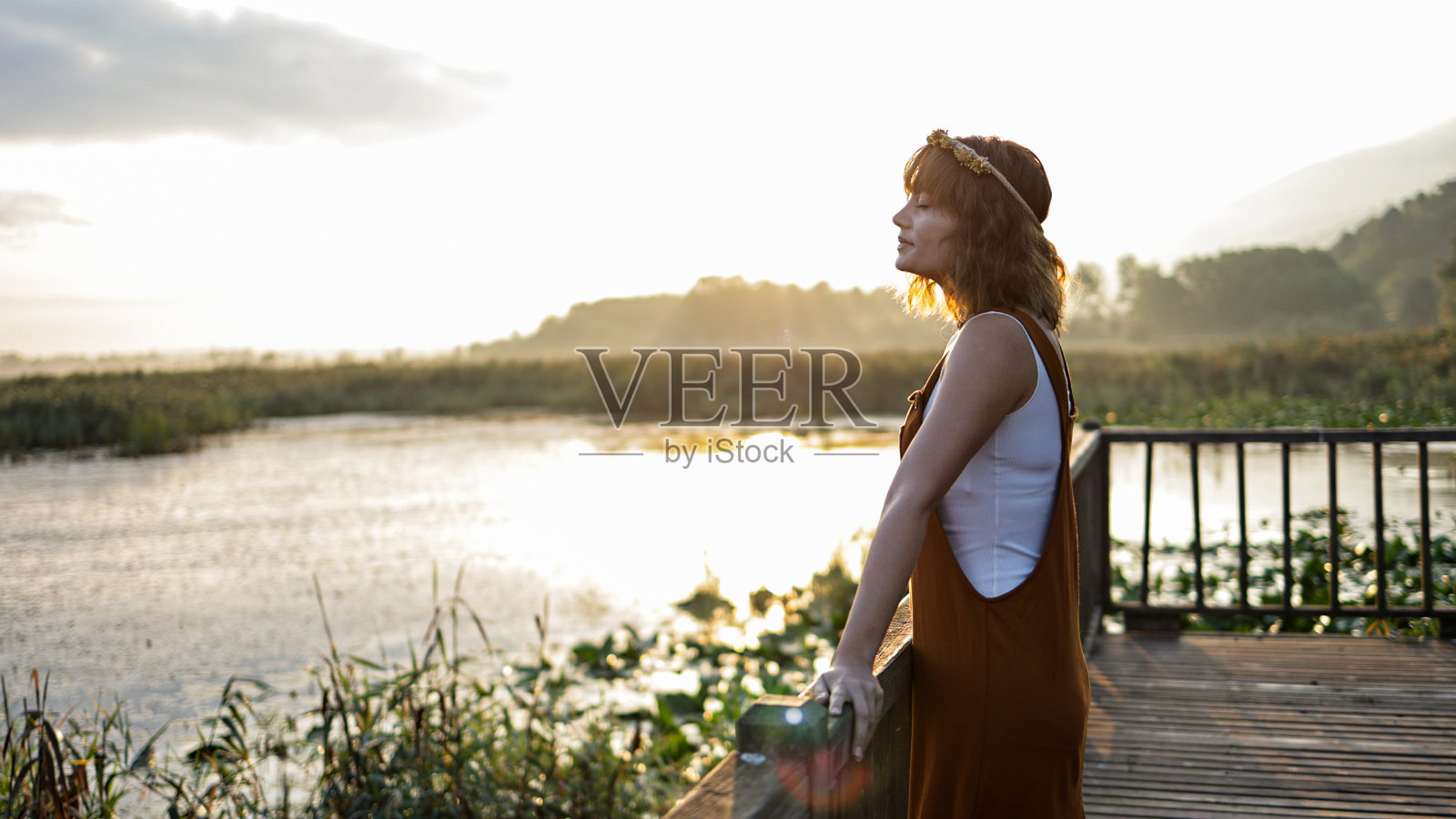 年轻漂亮的女人在埃夫特尼湖的码头上迎接太阳照片摄影图片
