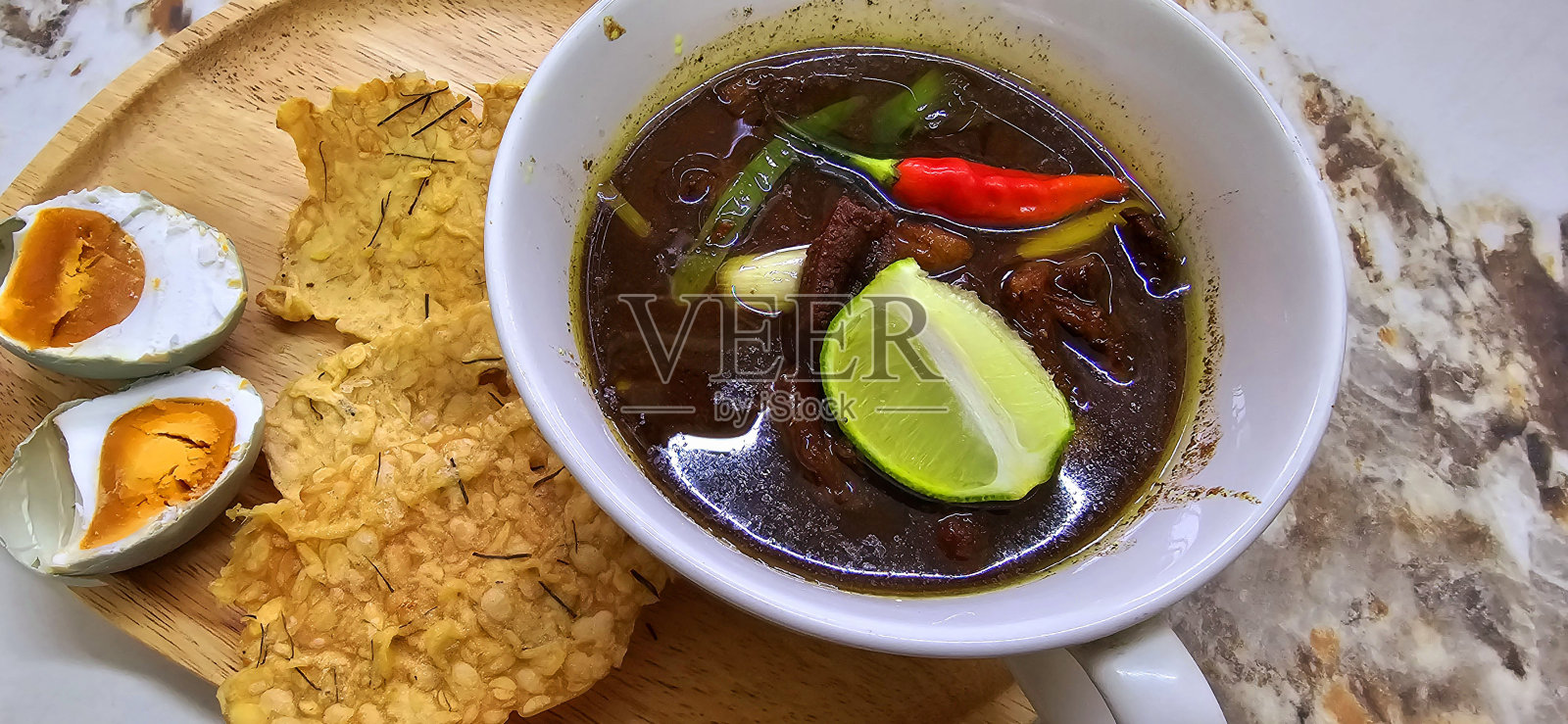 拉旺或印尼黑牛肉汤,黑色的颜色是来自印尼坚果叫kluwek。配上酸橙、辣椒酱、咸蛋和坦佩饼干。适合食谱,文章,或任何烹饪内容或博客照片摄影图片