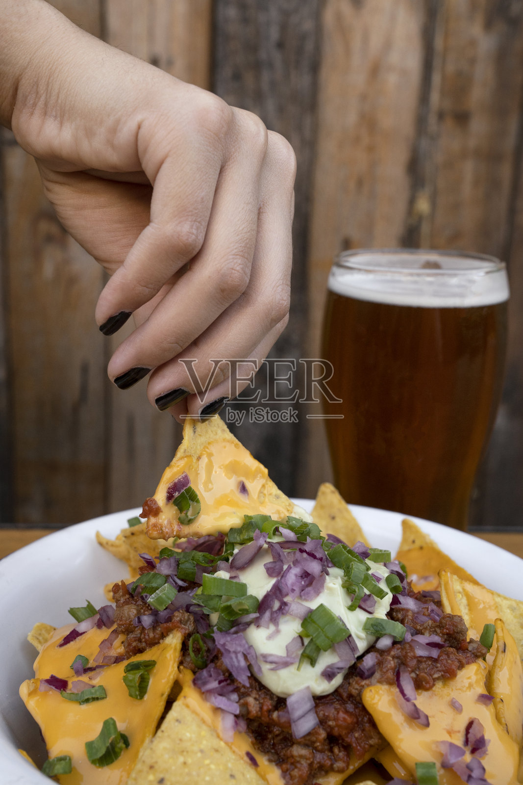 一个女人喝着啤酒,吃着美味的玉米片的特写照片摄影图片