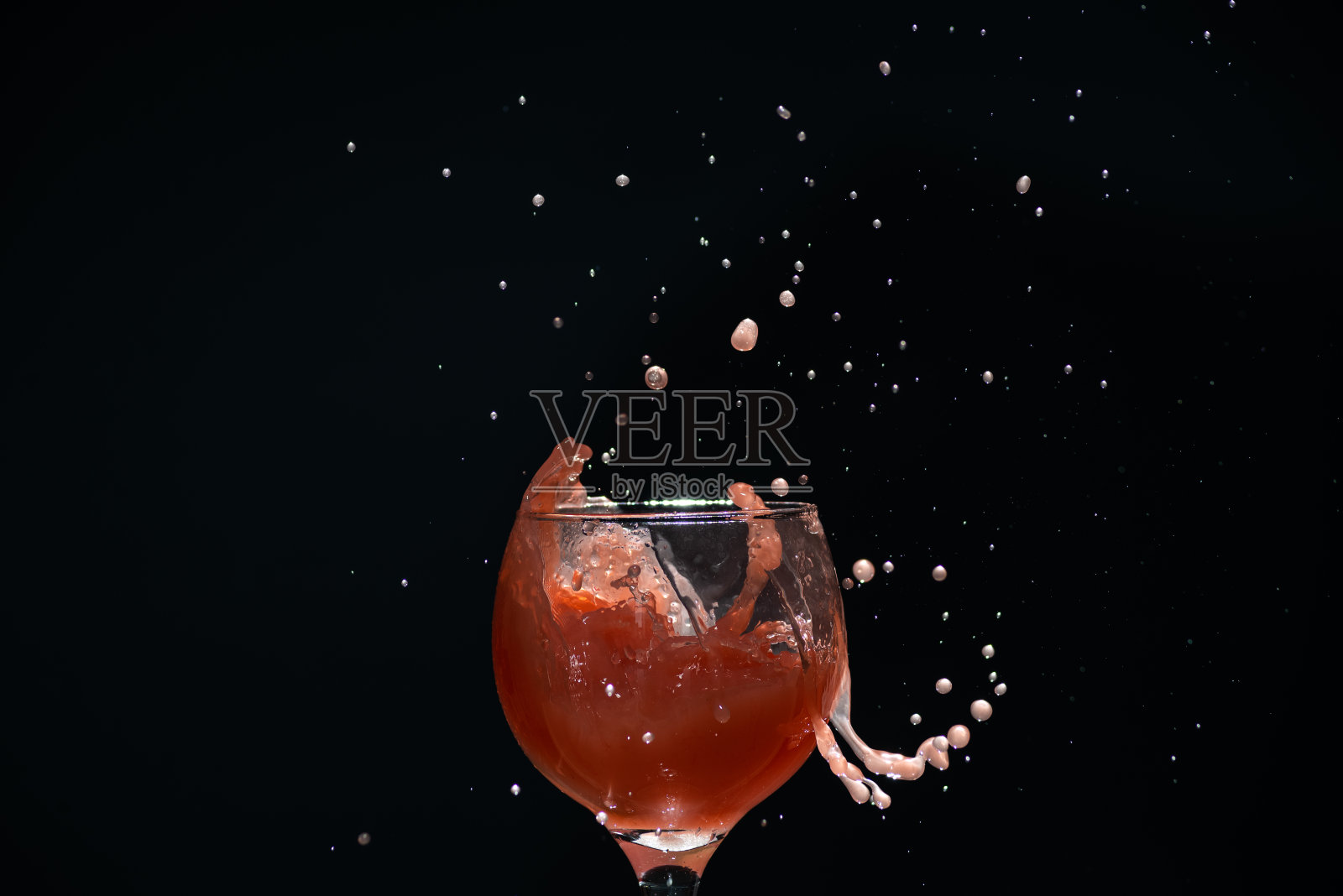 一个玻璃杯,里面有番石榴汁,会溅出水花。孤立在黑暗的背景。照片摄影图片