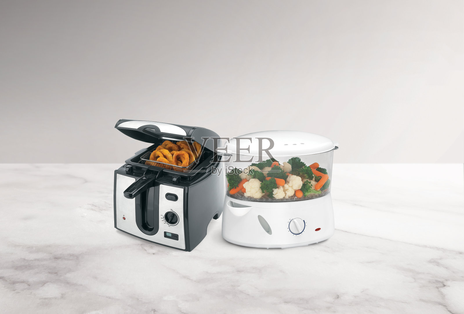 健康vs不健康有洋葱圈的油炸锅和有蔬菜的蒸锅照片摄影图片