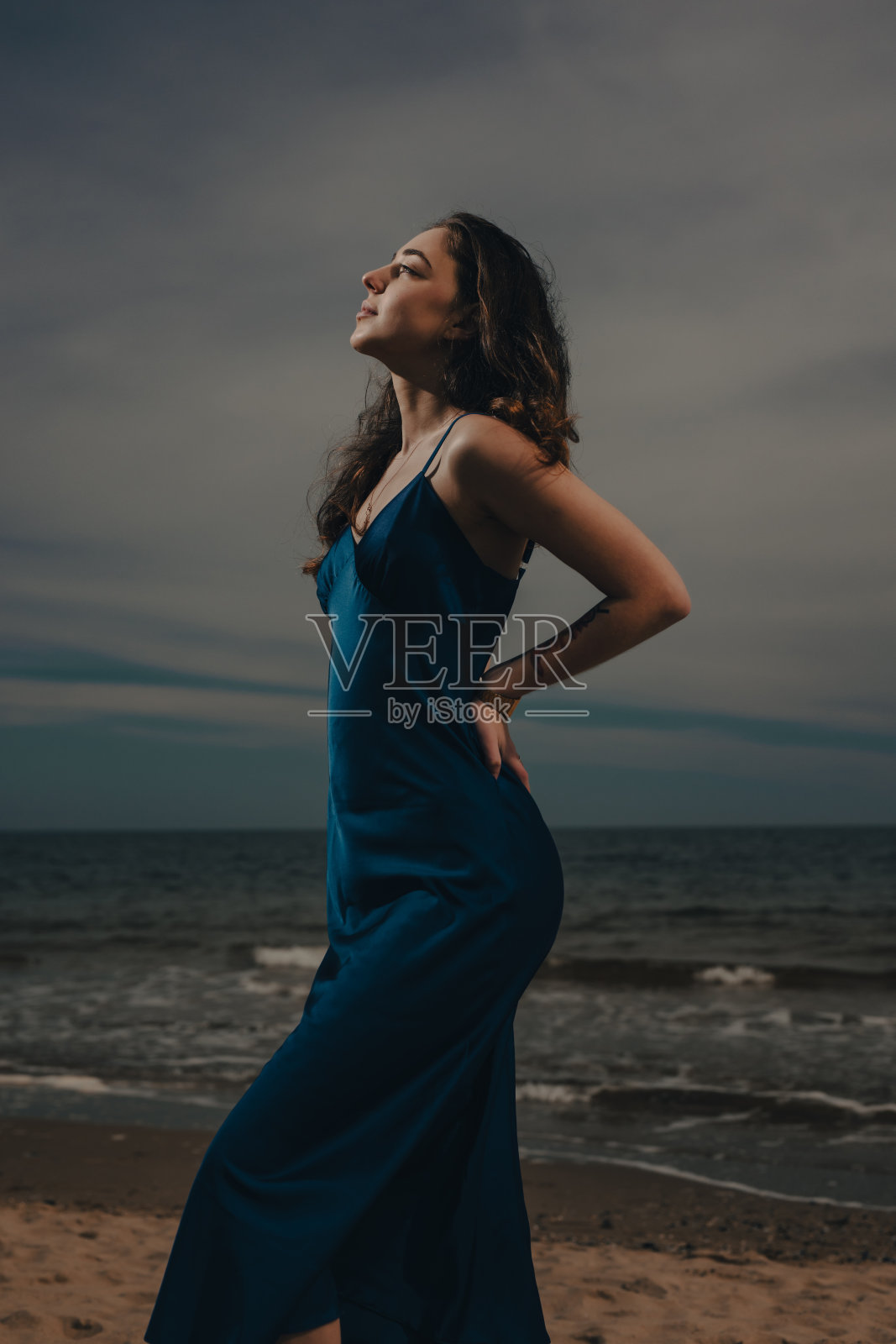 沙滩上穿着裙子的女人,背景是黑暗的天空照片摄影图片