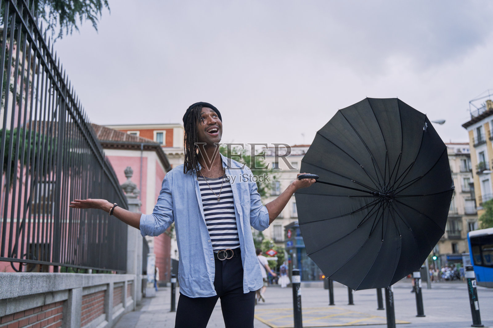 有魅力的非洲男人拿着伞,看是否下雨照片摄影图片