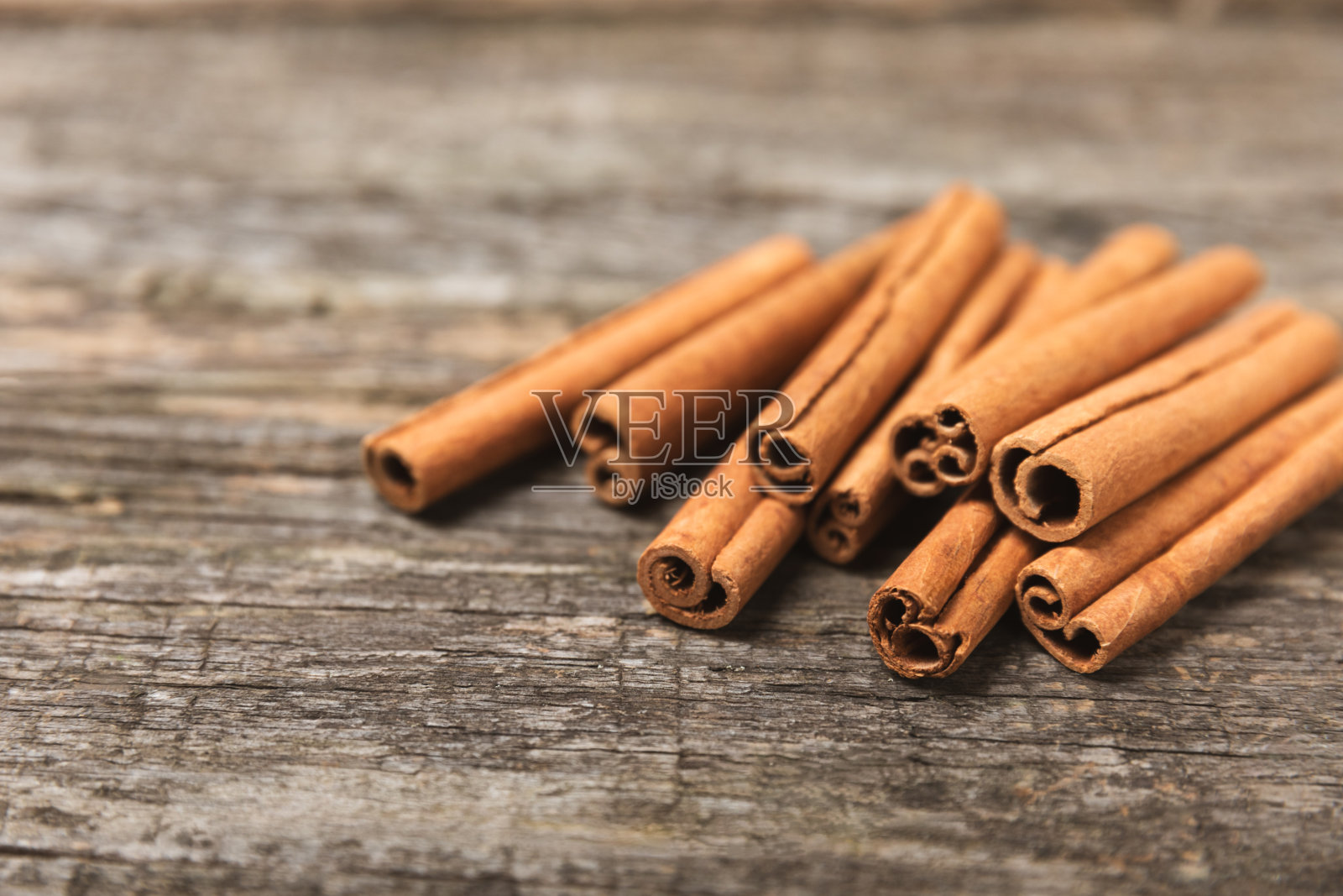 肉桂棒在有纹理的木制背景。肉桂卷。用于烘焙、甜点和饮料的辛辣香料。芳香的肉桂粉。肉桂粉特写。放文字的地方。本空间照片摄影图片