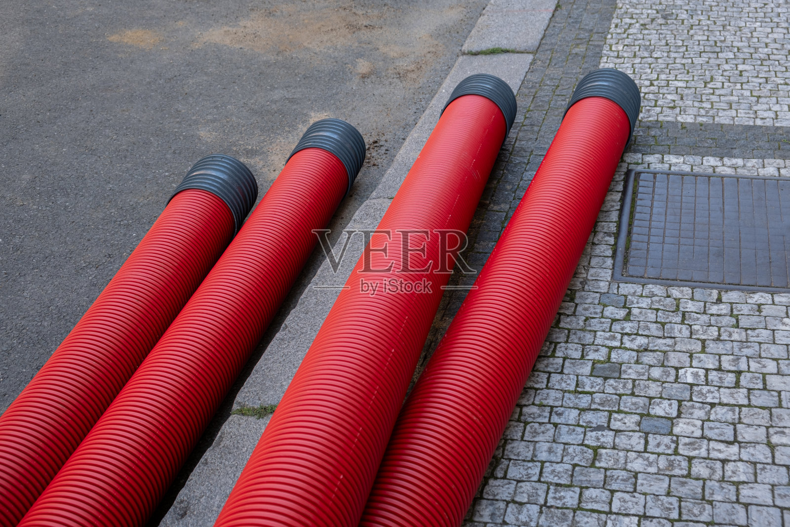 红色波纹管埋在街道地下。地下电缆基础设施安装。有很多通信电缆的建筑工地照片摄影图片