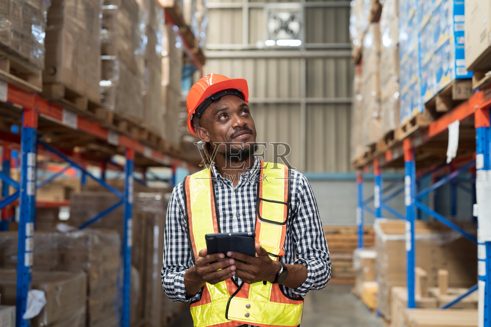 男性仓库工人在仓库工作时手持药片。仓库工人检查货架上的产品质量并检查库存照片摄影图片