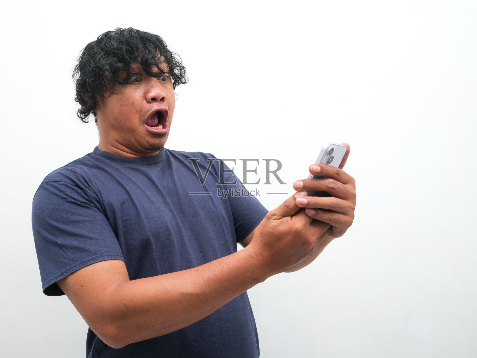 一名亚洲男子震惊了他在智能手机上看到的孤立的白色背景。照片摄影图片