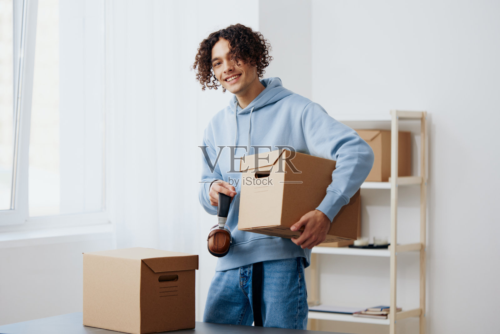 一个戴着耳机的年轻人拿着盒子在整理东西照片摄影图片