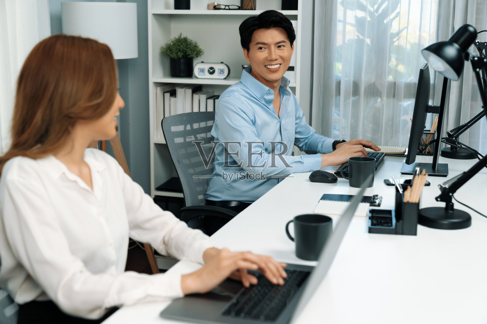 微笑的亚洲男人在笔记本电脑上与项目中的女同事交谈。信息高速公路。照片摄影图片