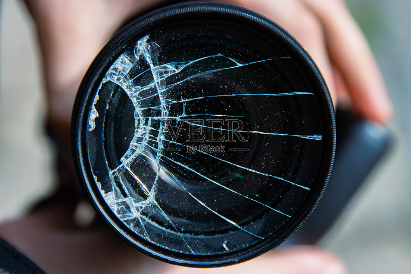 年轻摄影师的手拿着数码单反相机,镜头滤镜玻璃碎掉在地上。关闭了。破损的照片滤镜。宏。前视图。有选择性的重点。照片摄影图片