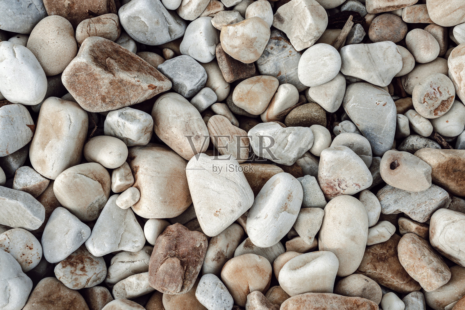 天然岩石纹理的彩色鹅卵石在沙滩上。自然背景。照片摄影图片