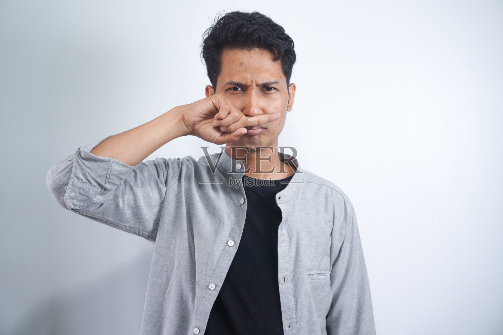 厌恶的人的肖像用手指捏鼻子,双手厌恶地看着有什么东西发臭难闻的情况孤立在灰色的墙壁背景。人的面部表情、肢体语言反应照片摄影图片