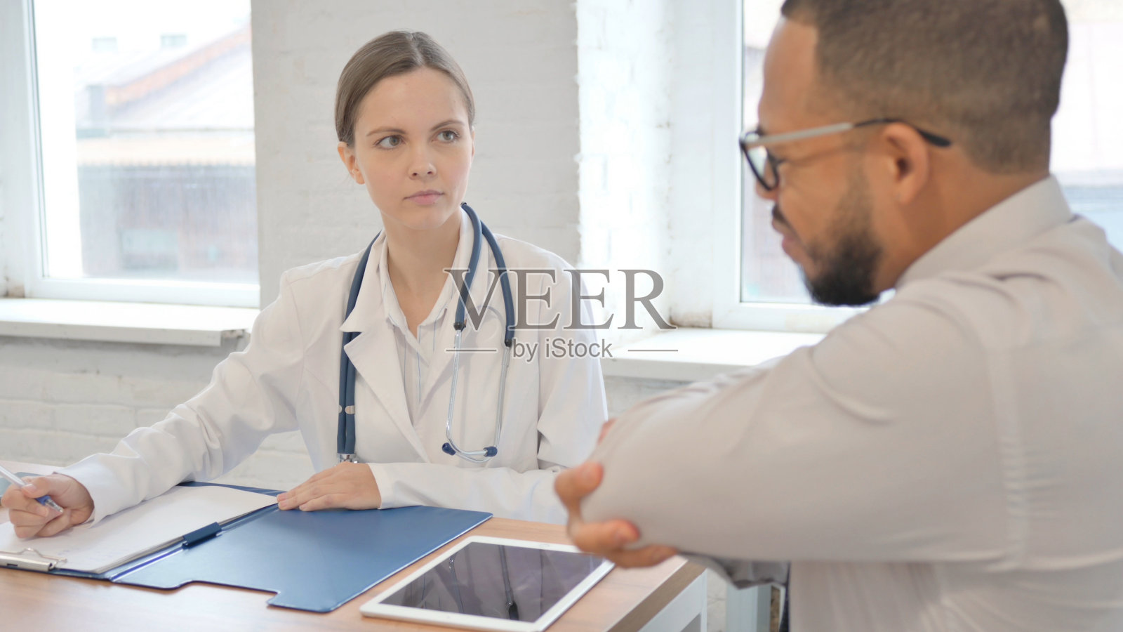 非洲男子肘部疼痛咨询整形女医生照片摄影图片