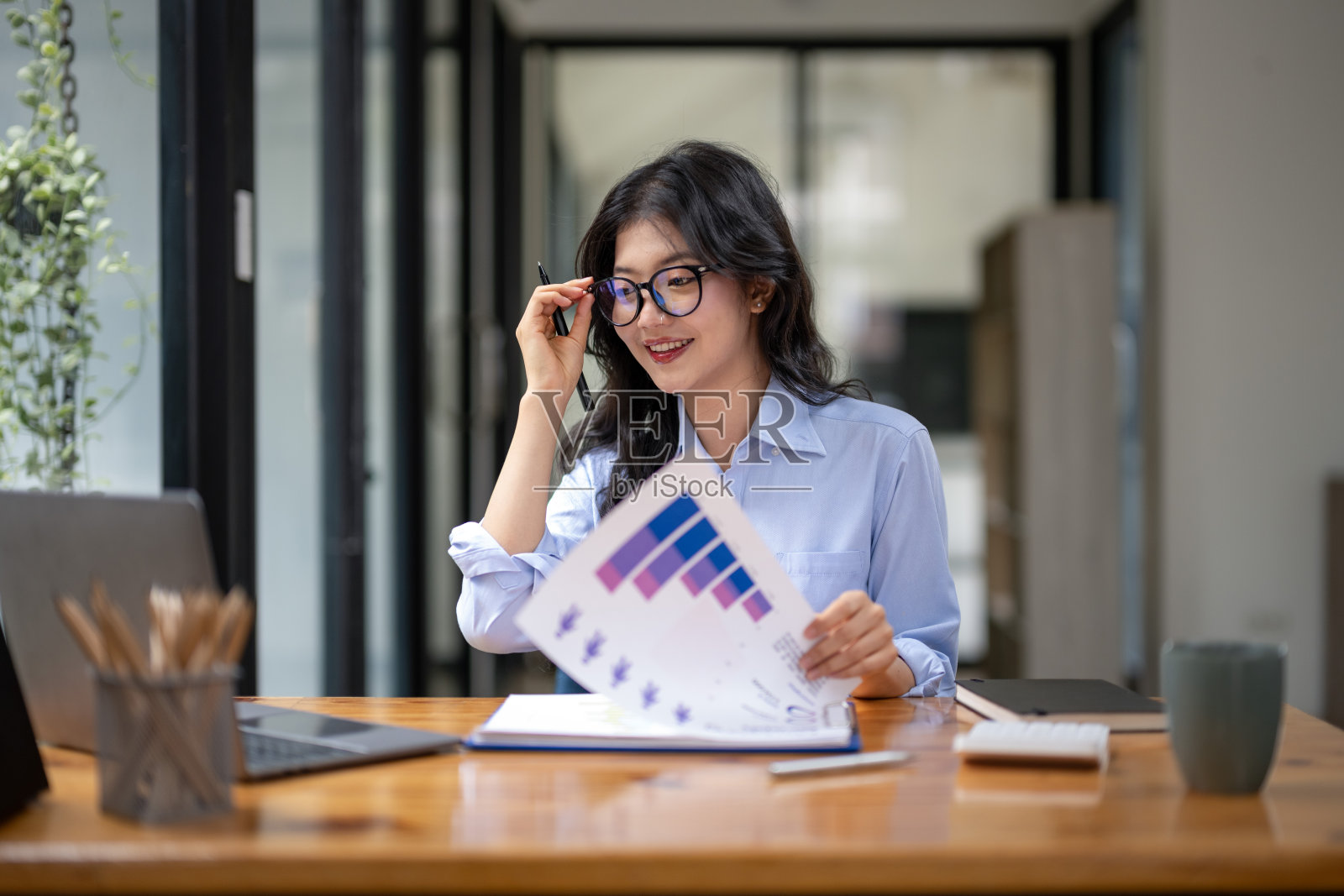 戴眼镜的女商人用笔记本电脑查看市场数据照片摄影图片
