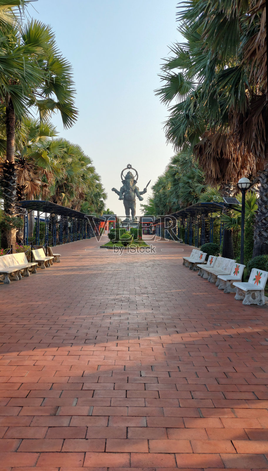 巨大的甘尼萨神矗立在一排棕榈树中,泰国。照片摄影图片