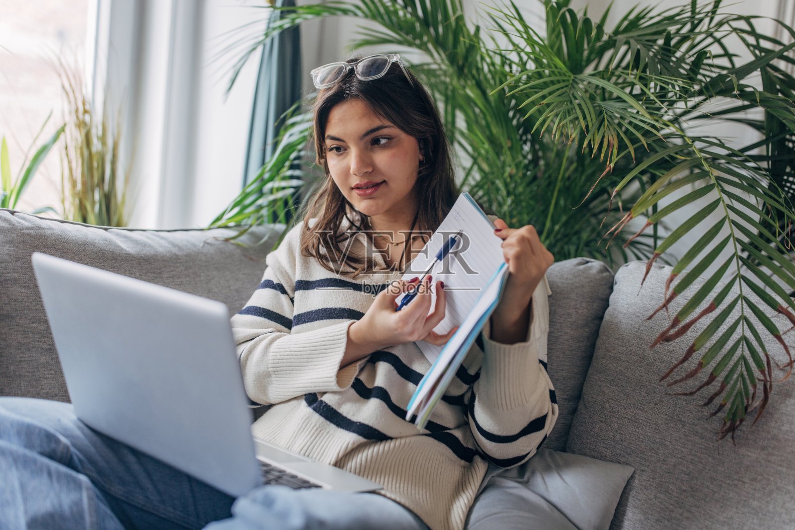 年轻女性用笔记本电脑和笔记本远程工作照片摄影图片