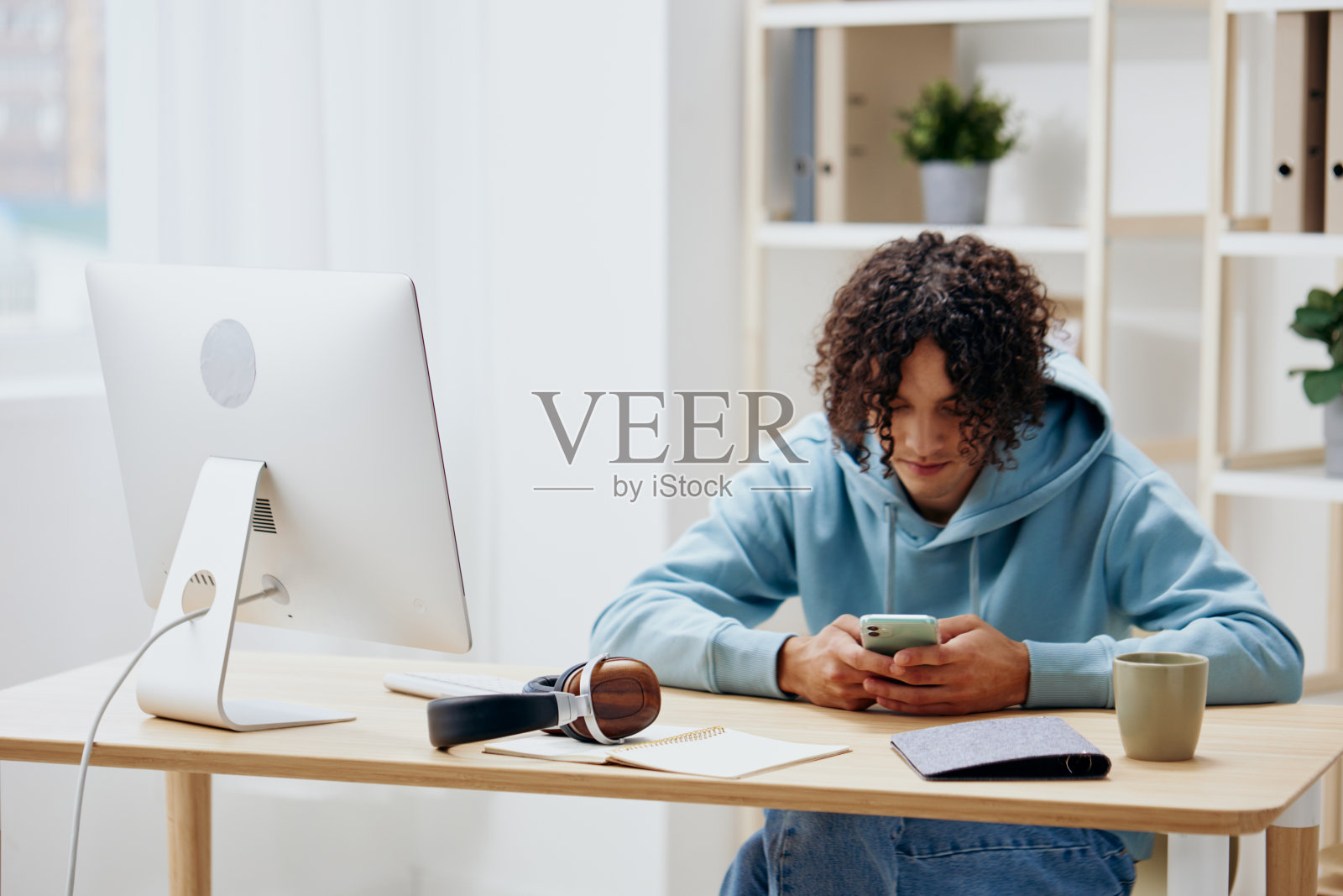 一个年轻人坐在电脑前的桌子旁照片摄影图片