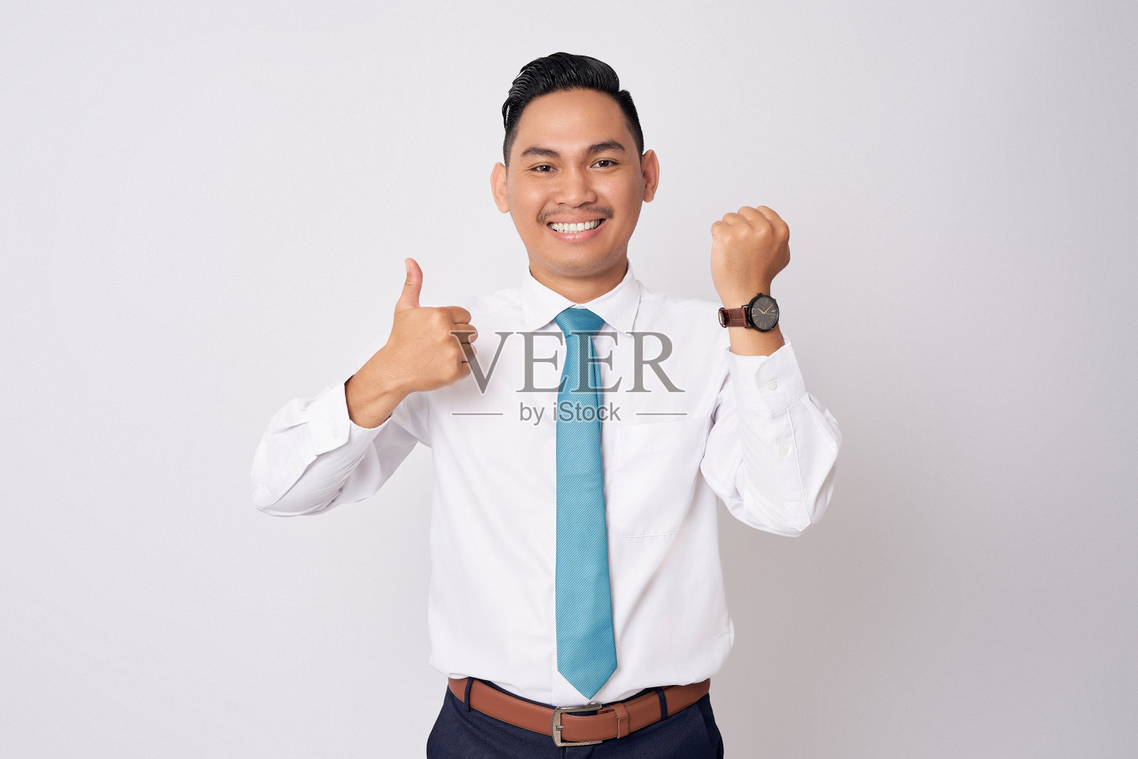 微笑的年轻亚洲商人雇员公司律师穿着正式的衬衫领带显示手表和大拇指孤立在白色背景照片摄影图片