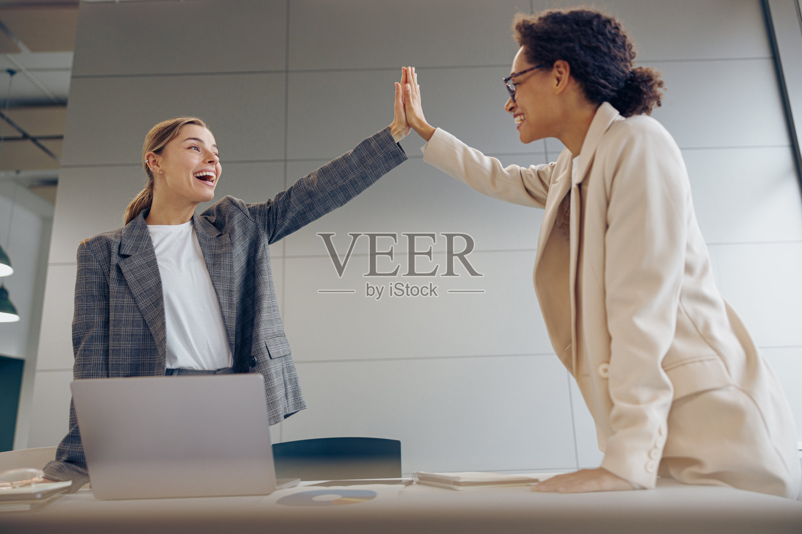 快乐的商务人士在共同办公的笔记本电脑上互相击掌照片摄影图片