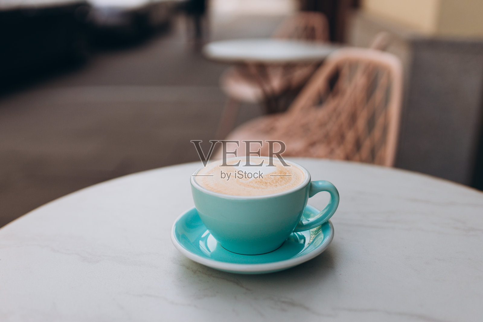 蓝杯卡布奇诺,还有拉花。咖啡馆的桌子上有蓝色杯子里的咖啡。咖啡休息。特写镜头。照片摄影图片