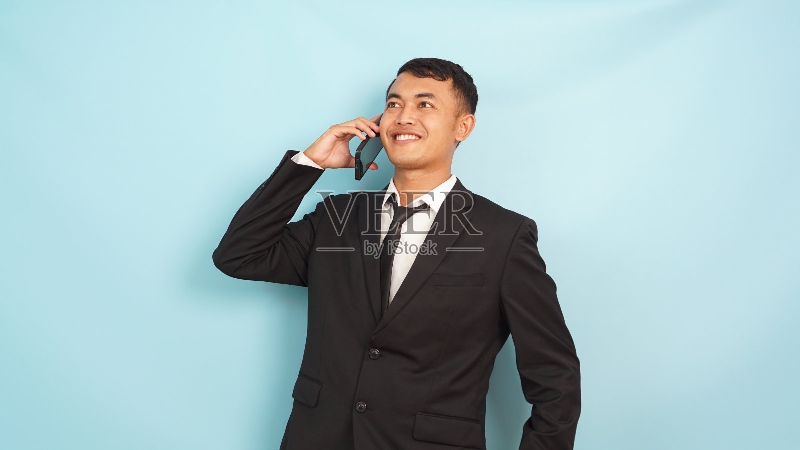 年轻的亚洲商人用手机打电话,谈生意,孤立的蓝色背景照片摄影图片