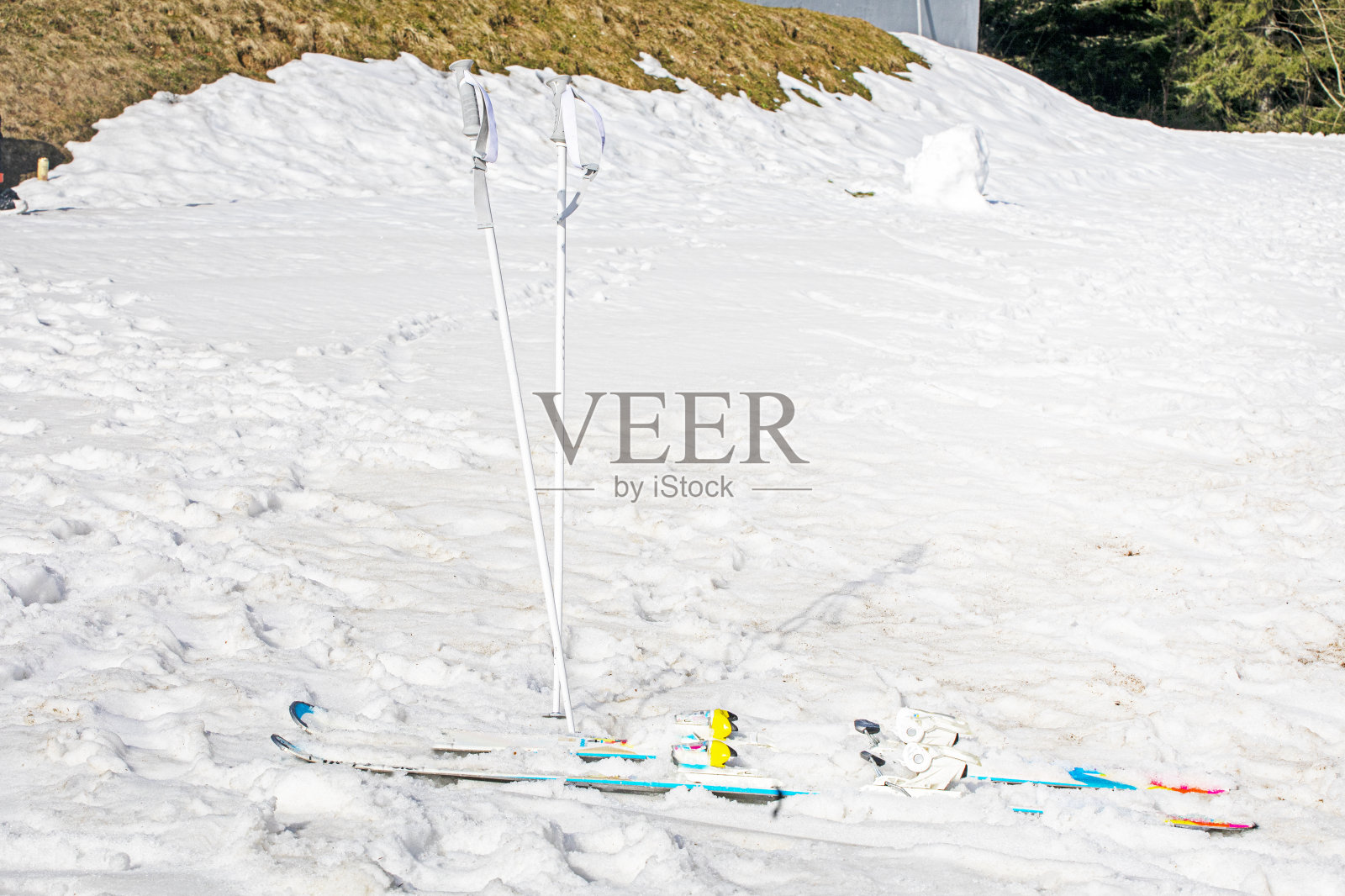 在阳光明媚的日子里,滑雪杖和滑雪板在雪坡上滑行照片摄影图片