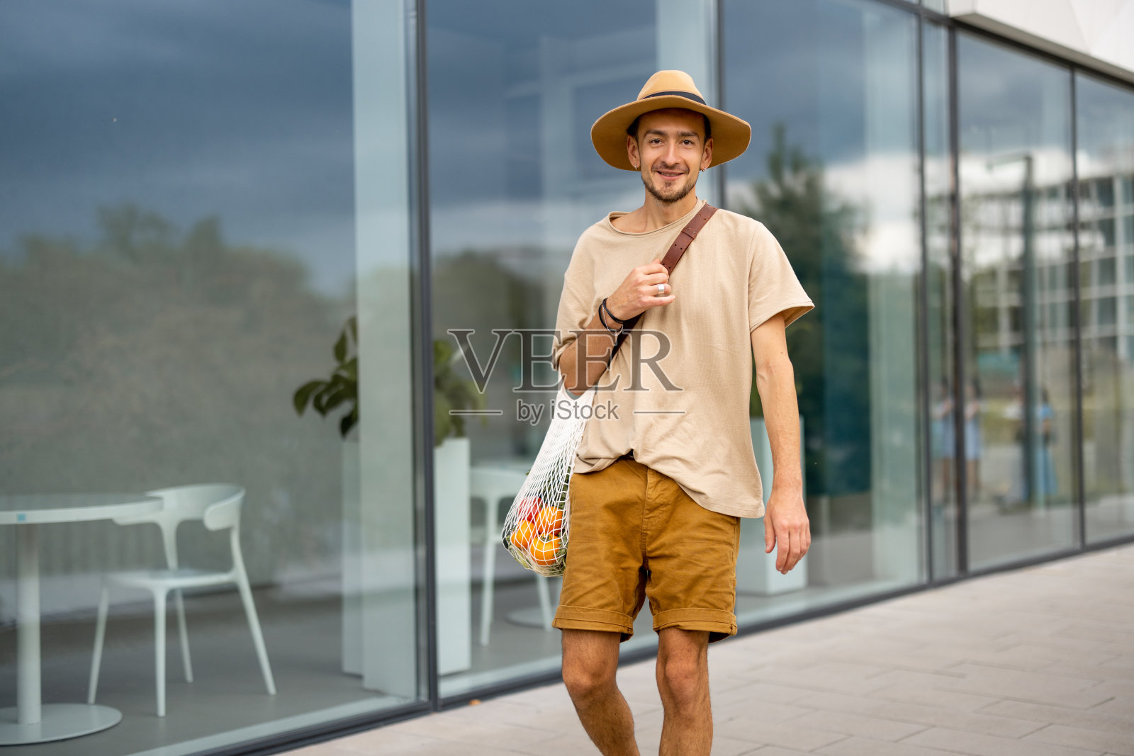 一个男人带着一个装满新鲜蔬菜的网袋走在户外照片摄影图片