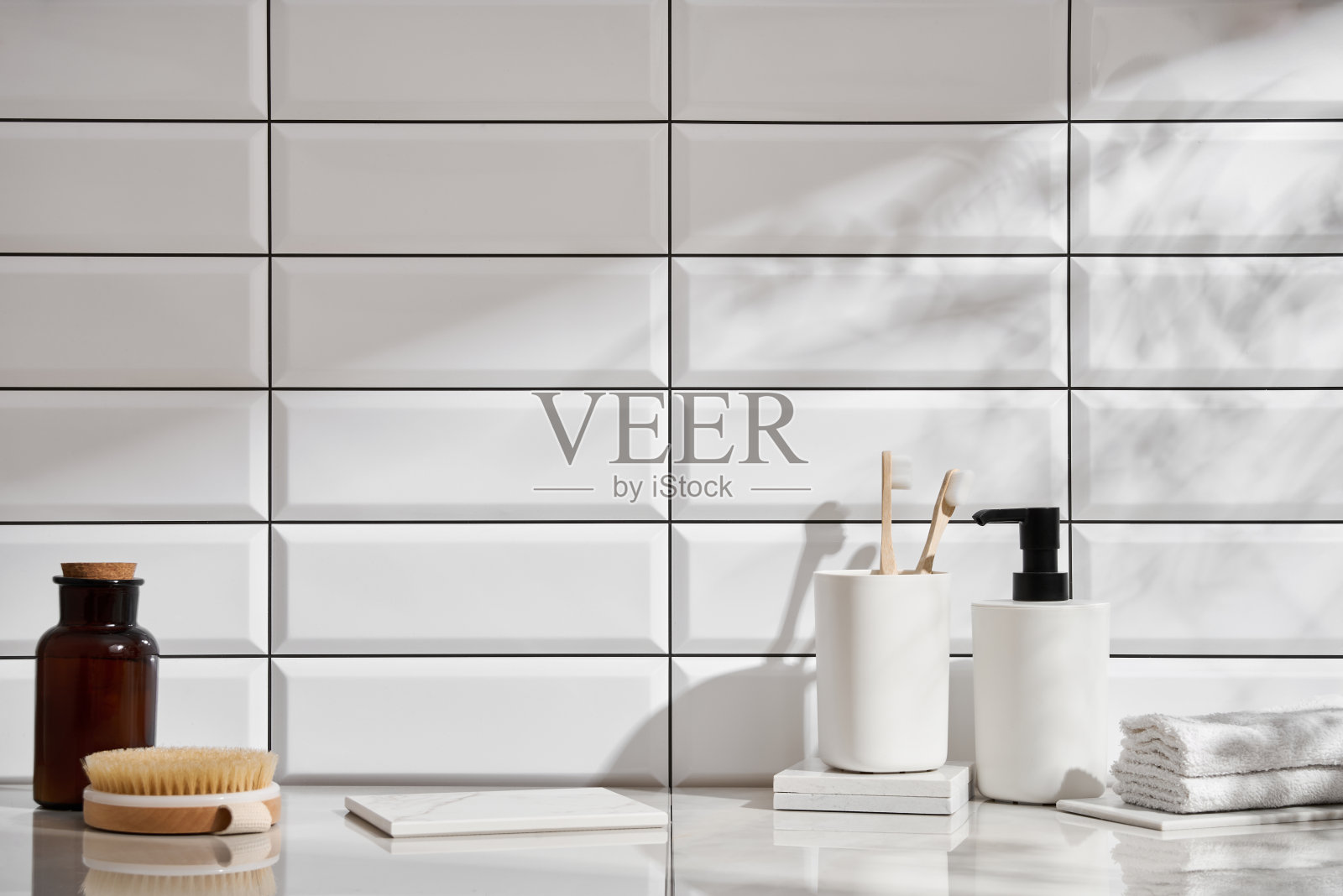 浴室里的大理石架子上摆放着各种物品,背景是白色瓷砖照片摄影图片