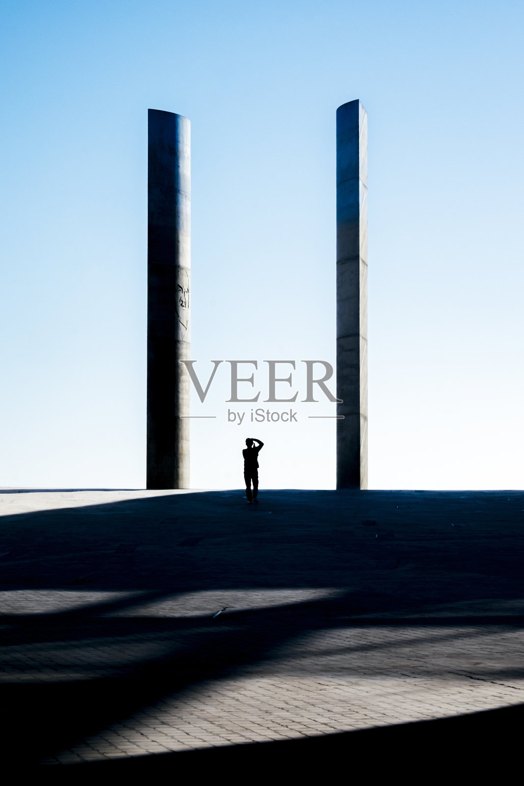 一个人给现代建筑的石柱拍照。照片摄影图片