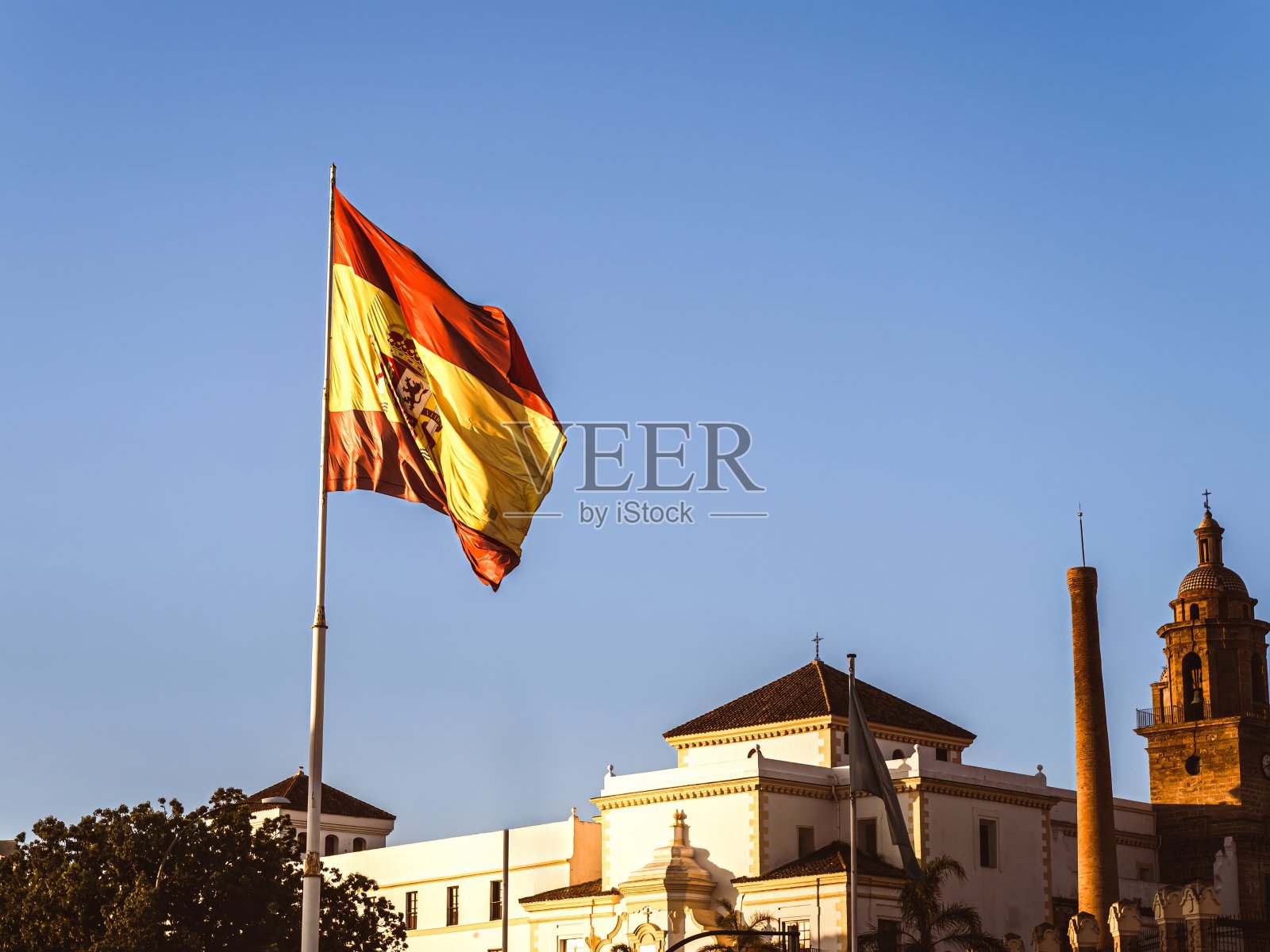 在早晨的黄金时段,西班牙国旗飘扬在加的斯市上空照片摄影图片