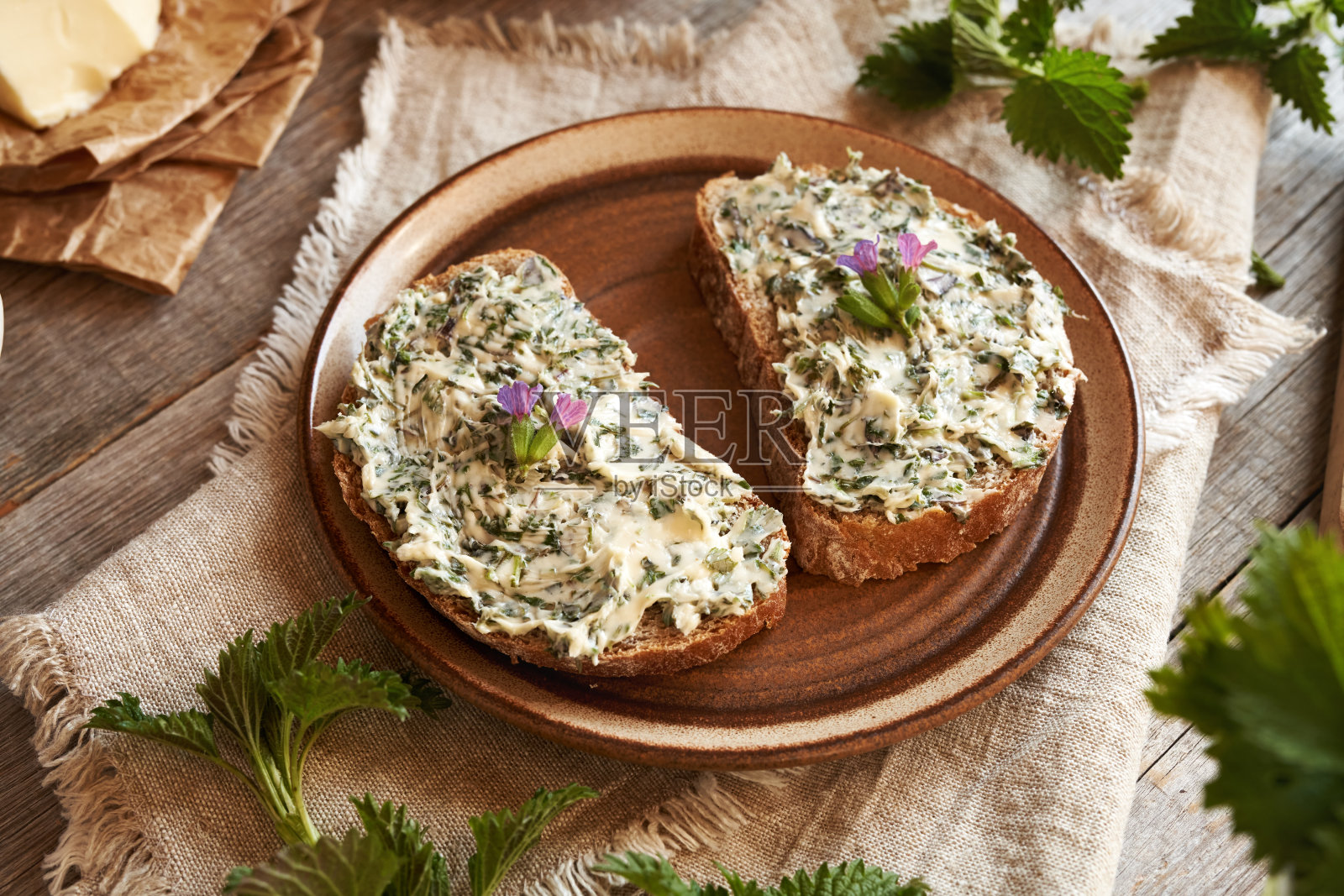 荨麻黄油-自制的面包酱,由春天收获的野生可食用植物制成,有肺草花照片摄影图片