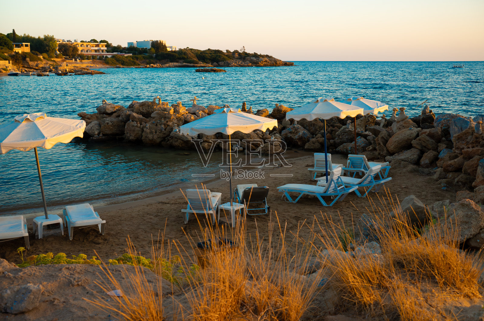 舒适的小沙滩和日落时的日光浴躺椅。照片摄影图片