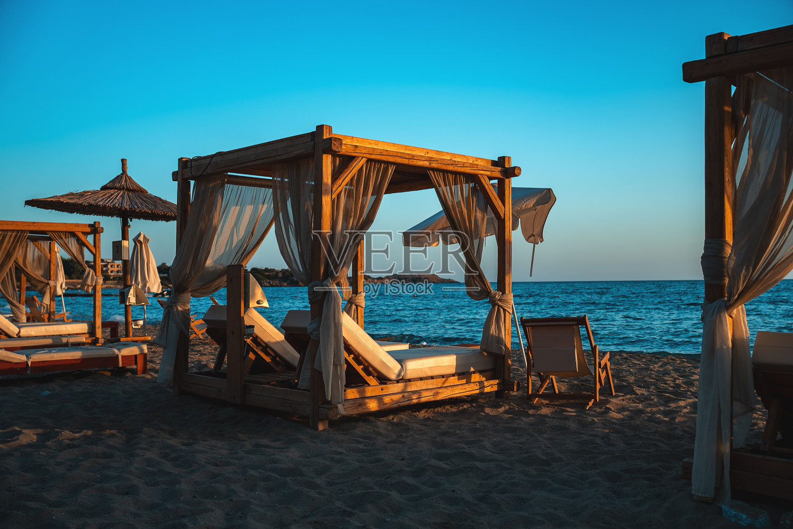 日落时海边的沙滩小屋床和日光浴躺椅。照片摄影图片